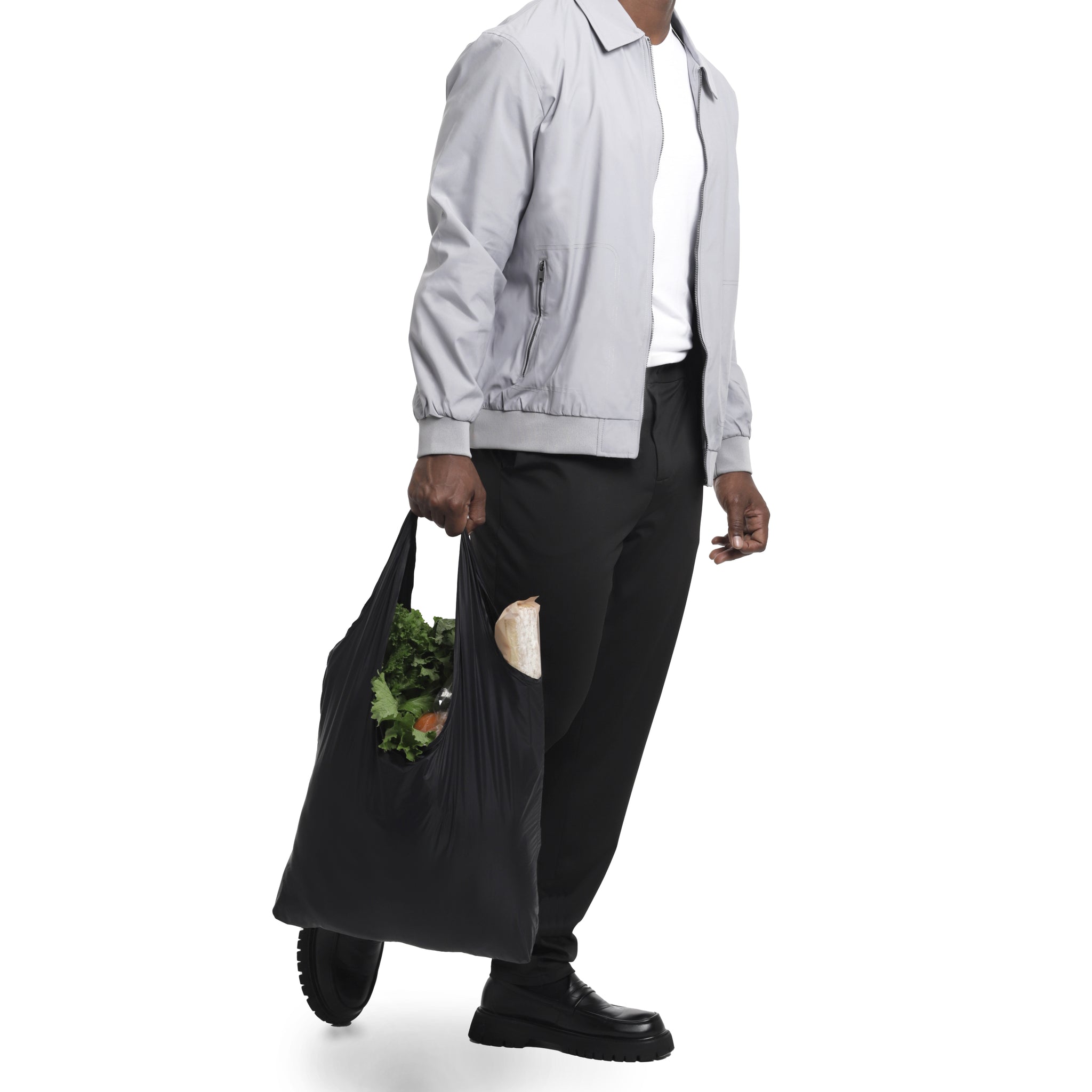 A man holding a KYVOS bag carrying groceries in a white background setting.